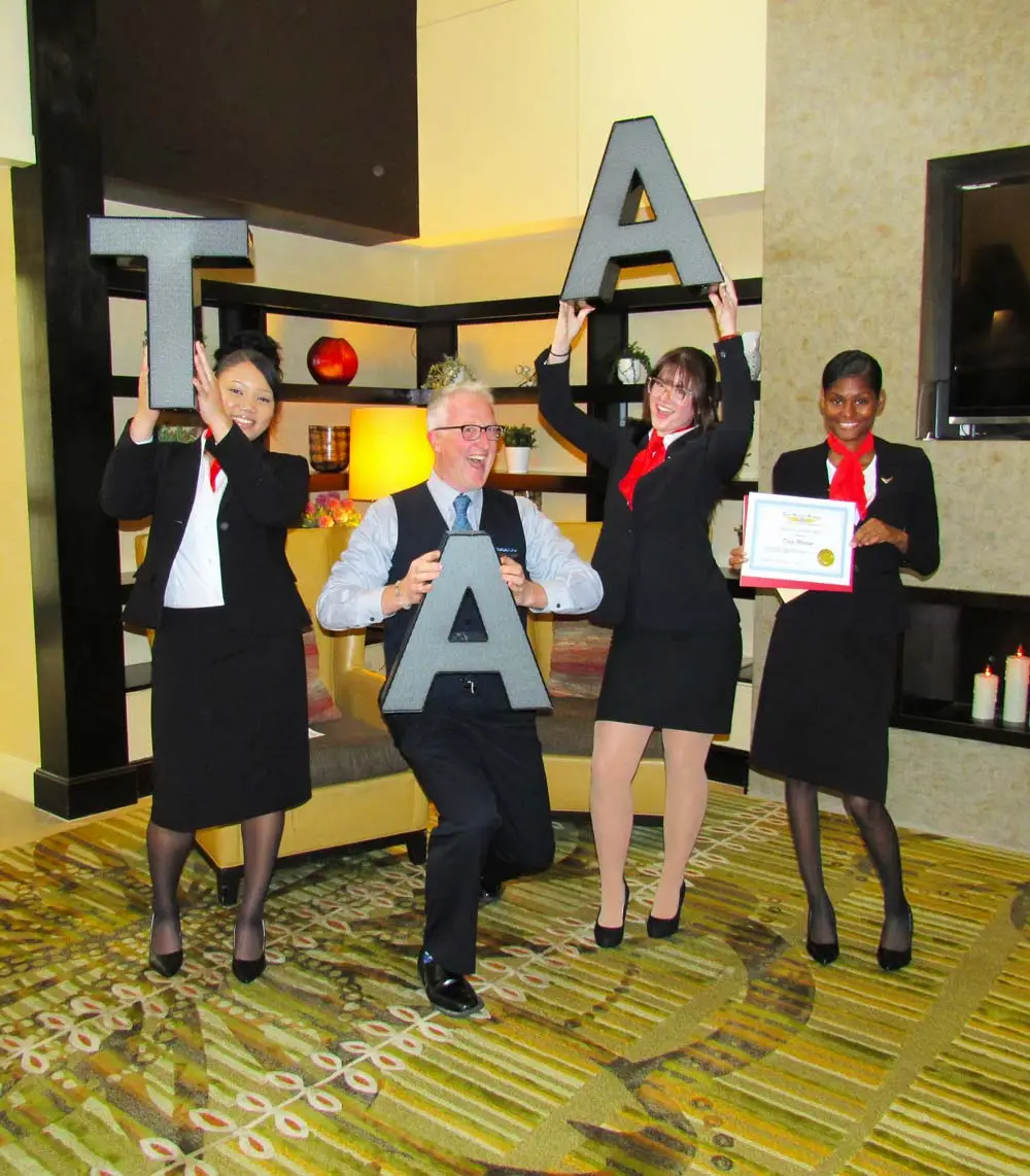 Flight attendant crew holding TAA letters with a graduate holding a certificate