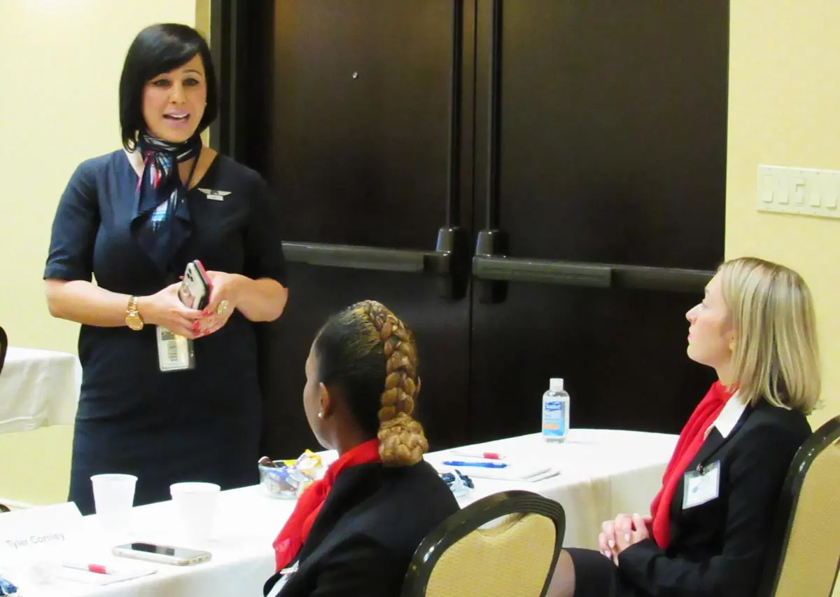 Instructor talking honestly with two seated Flight Attendant Preparation Program students