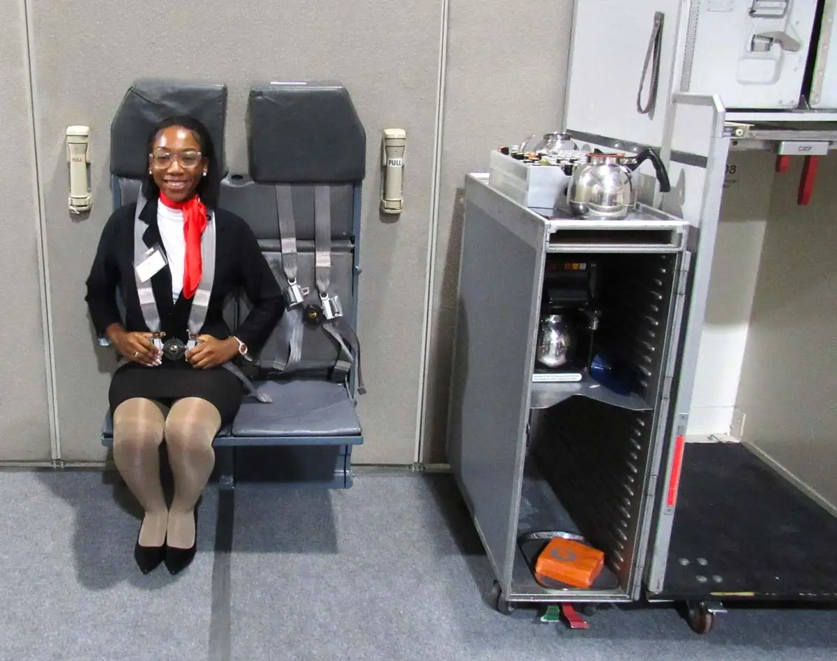 Flight attendant student buckling a seatbelt during training