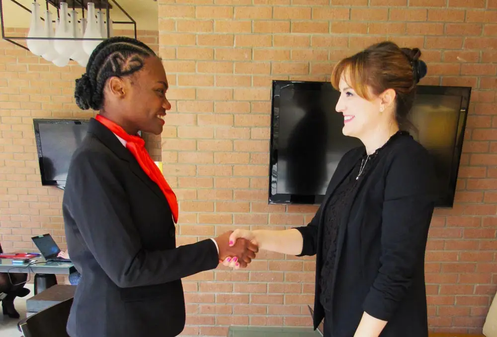 Flight attendant graduate shaking hands with an airline recruiter