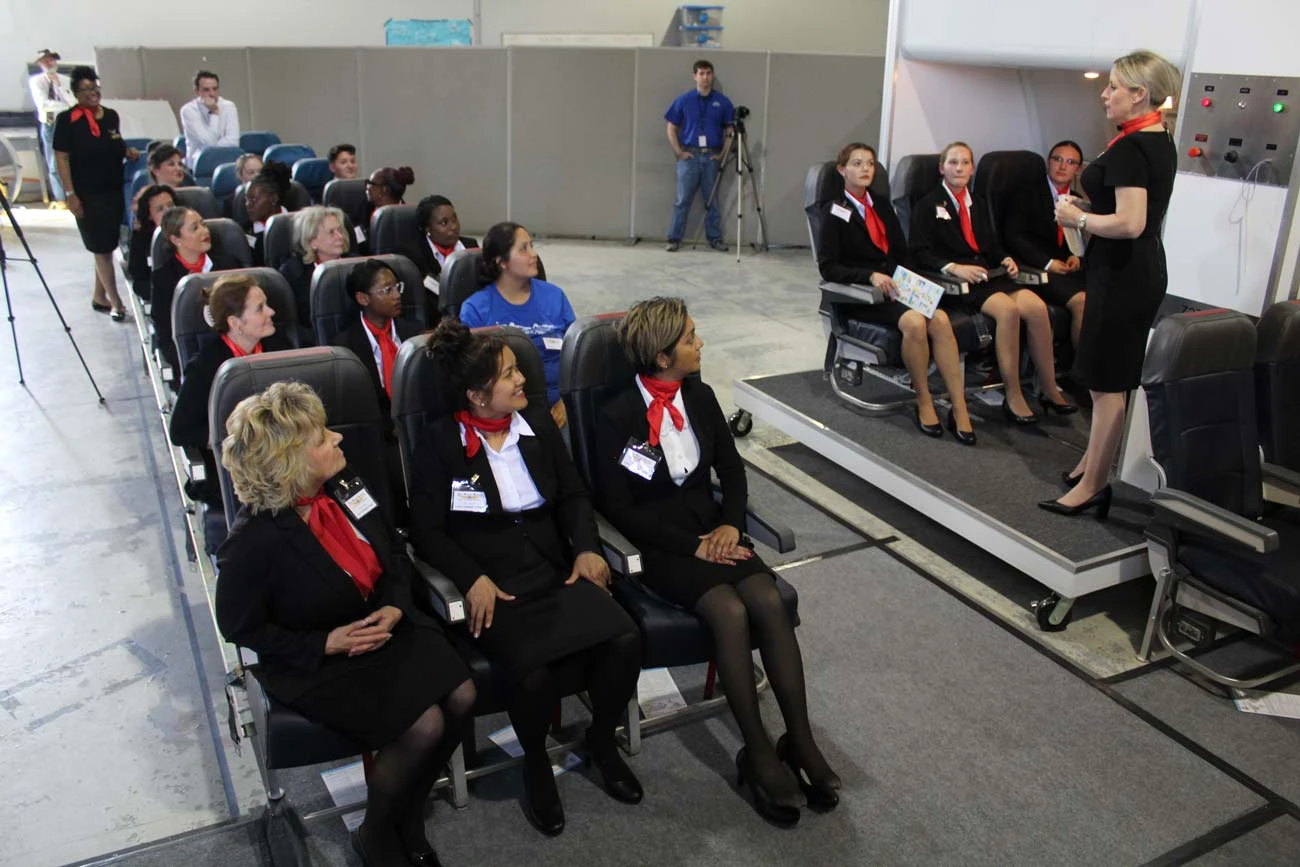 Flight attendant students practicing cabin procedures in aircraft seat mockup