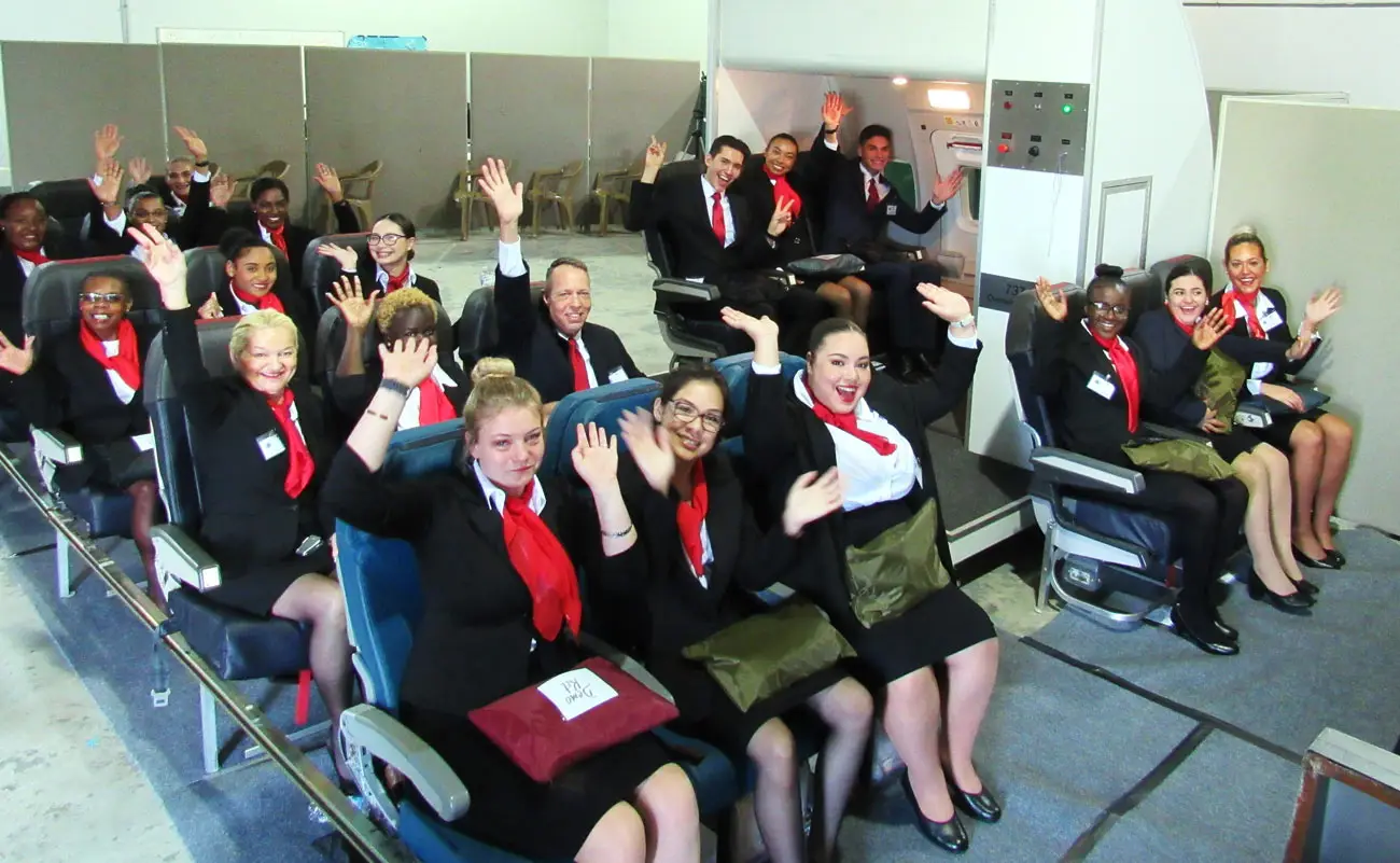 Flight attendant students raising their hands in the mock cabin