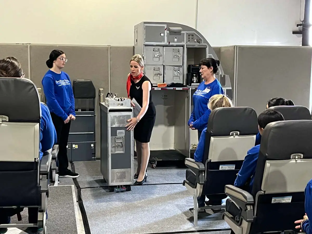 Flight attendant students with an in-uniform attendant on stage