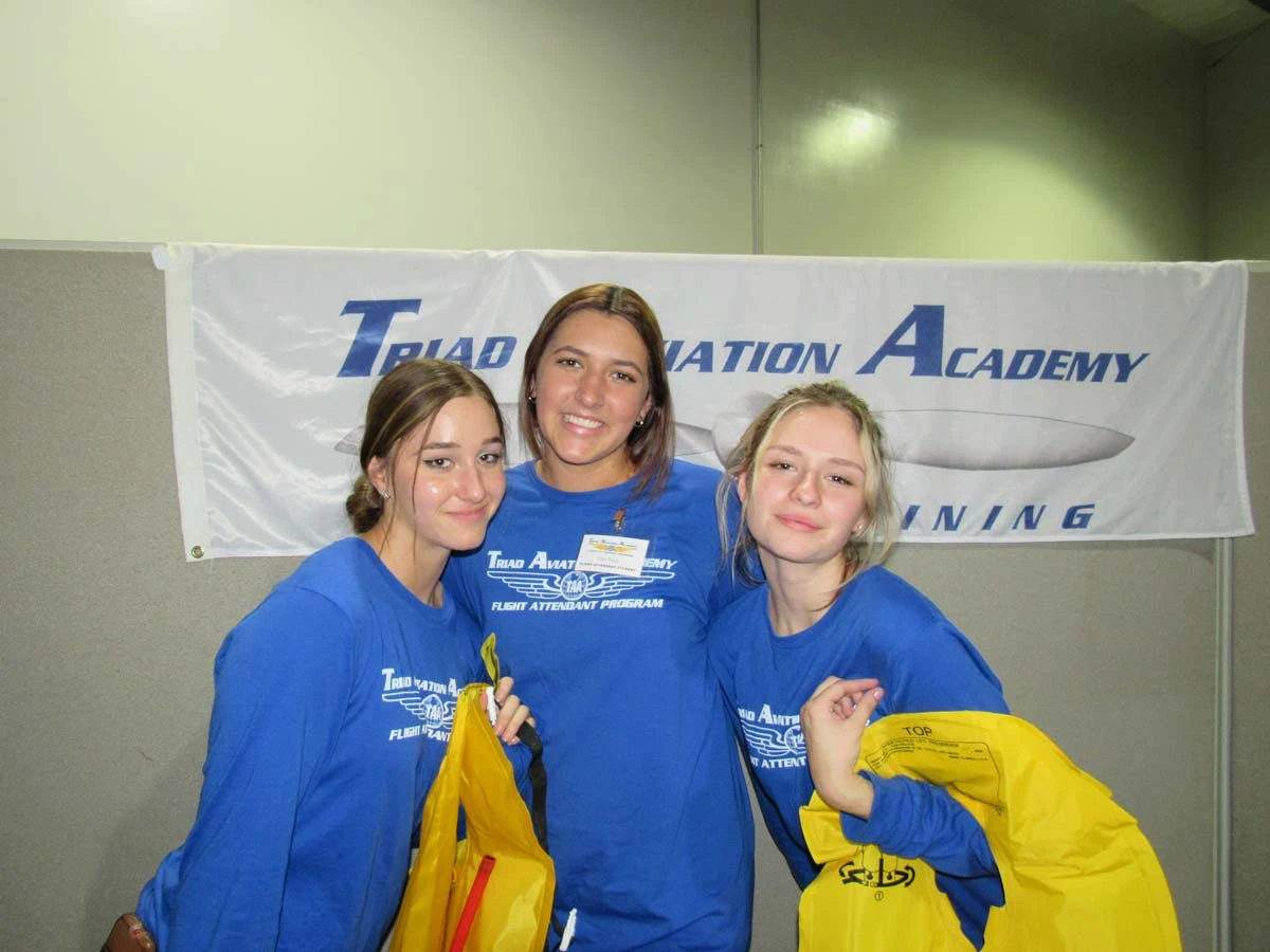 Flight attendant students posing together with TAA gear